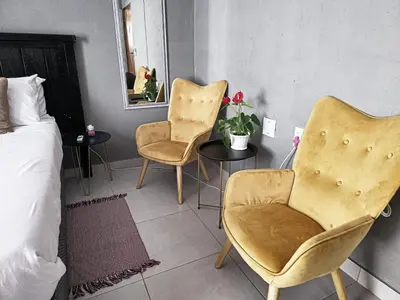 a bedroom with two chairs and a bed and a mirror at Akwaaba Fie Guesthouse in Lebowakgomo