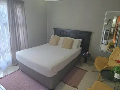 a bedroom with a large bed with white sheets and pillows at Akwaaba Fie Guesthouse in Lebowakgomo