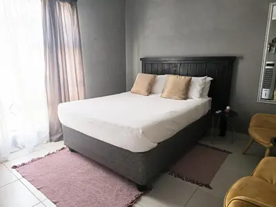 a bedroom with a large bed with white sheets and pillows at Akwaaba Fie Guesthouse in Lebowakgomo