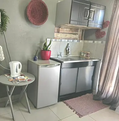 a small kitchen with a sink and a table at Akwaaba Fie Guesthouse in Lebowakgomo