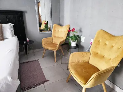 a bedroom with two chairs and a bed and a mirror at Akwaaba Fie Guesthouse in Lebowakgomo