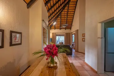 a vase of flowers on a wooden table in a room at Kruger Park Lodge Unit 526 in Hazyview