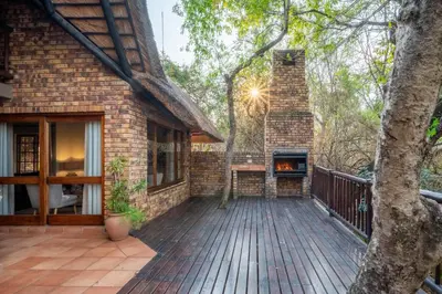 a brick house with a deck with a fireplace at Kruger Park Lodge Unit 526 in Hazyview