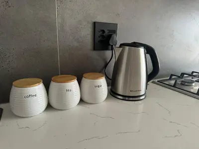 three white cups sitting on a counter next to a coffee maker at Business trip or Fun with the Family - you decide! in Pretoria