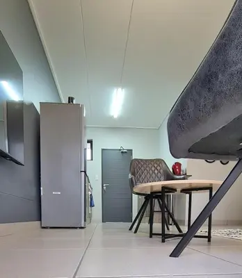 a room with a table and a chair and a refrigerator at Convenient Corner of GreenValley estate in Nelspruit