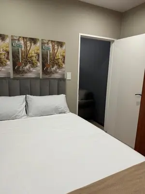 a bedroom with a white bed and paintings on the wall at Closer to CBD by UrbanCove in Nelspruit