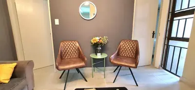 two chairs and a table in a room with a mirror at Closer to CBD by UrbanCove in Nelspruit