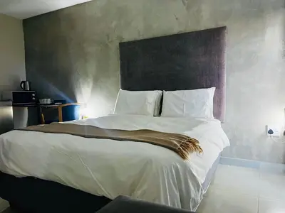a bedroom with a large bed with white sheets at TLS Cottages in Buffelspruit