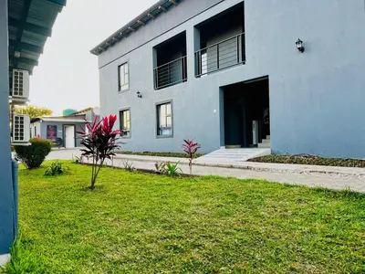 a blue building with a grassy yard in front of it at TLS Cottages in Buffelspruit