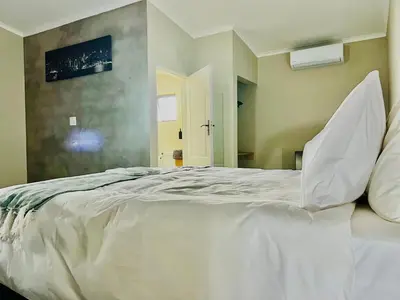 a large white bed with pillows in a room at TLS Cottages in Buffelspruit