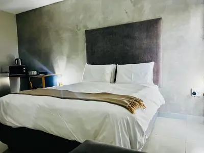 a bedroom with a large bed with white sheets at TLS Cottages in Buffelspruit