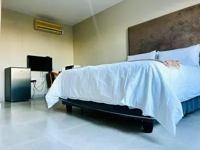 a bedroom with a bed with white sheets and a tv at TLS Cottages in Buffelspruit