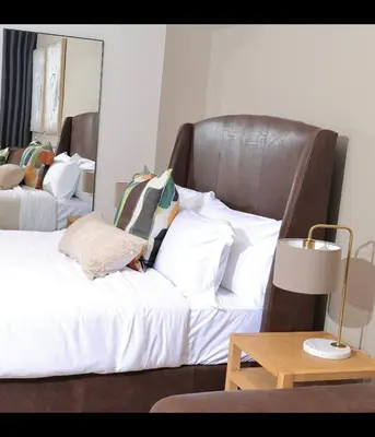 a bedroom with a large bed with a leather headboard at Brown, Warm and Cozy, Menlyn Maine Residences 926 in Pretoria