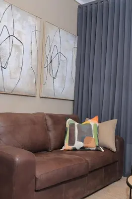 a brown couch with two pillows in a living room at Brown, Warm and Cozy, Menlyn Maine Residences 926 in Pretoria