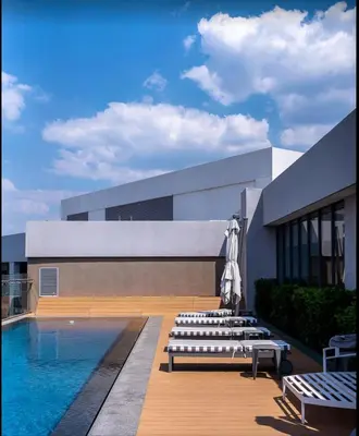 a building with a swimming pool and a group of benches at Brown, Warm and Cozy, Menlyn Maine Residences 926 in Pretoria