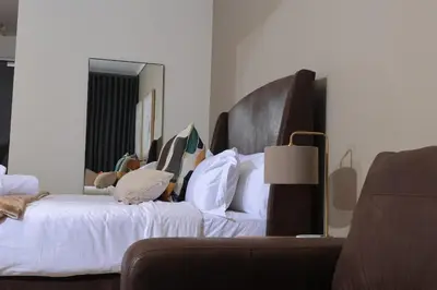 a bedroom with a large bed with white sheets and pillows at Brown, Warm and Cozy, Menlyn Maine Residences 926 in Pretoria
