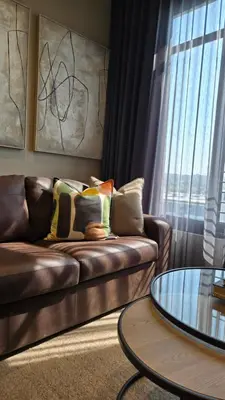 a living room with a leather couch and a glass table at Brown, Warm and Cozy, Menlyn Maine Residences 926 in Pretoria