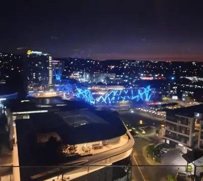 a view of a city at night with blue lights at Brown, Warm and Cozy, Menlyn Maine Residences 926 in Pretoria