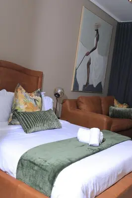 a bed with a green blanket and a couch at Green Serene Studio, Menlyn Maine Residences 826 in Pretoria