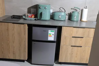a kitchen with a counter with a refrigerator under a table at Green Serene Studio, Menlyn Maine Residences 826 in Pretoria