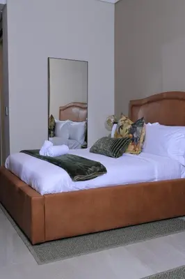 a large bed with white sheets and a large mirror at Green Serene Studio, Menlyn Maine Residences 826 in Pretoria