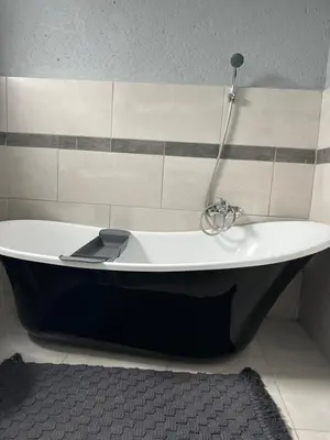 a bath tub with a shower in a bathroom at Fourteen38 Mews Guesthouse in Dwarsloop