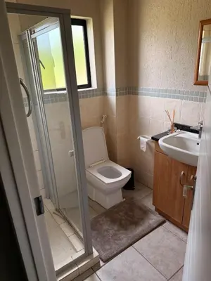 a bathroom with a shower and a toilet and a sink at Stylish Riverside Home with Pool, Braai & Wi-Fi in Nelspruit