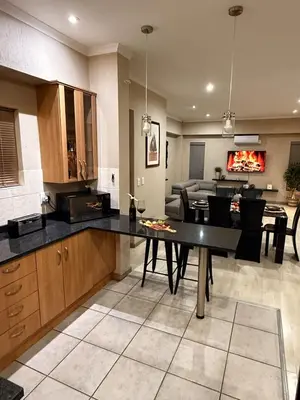 a kitchen and living room with a table and a couch at Stylish Riverside Home with Pool, Braai & Wi-Fi in Nelspruit