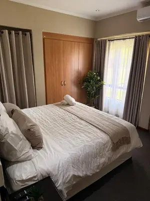 a bedroom with a large white bed with a window at Stylish Riverside Home with Pool, Braai & Wi-Fi in Nelspruit