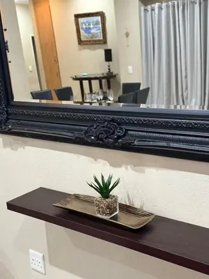 a mirror on a wall with a plant on a shelf at Stylish Riverside Home with Pool, Braai & Wi-Fi in Nelspruit