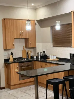 a kitchen with wooden cabinets and a counter top at Stylish Riverside Home with Pool, Braai & Wi-Fi in Nelspruit
