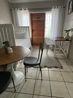 a living room with a table and chairs and a bed at Atterbury Value Bed and Breakfast Garsfontein in Pretoria