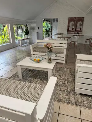 a living room with white benches and a table at Atterbury Value Bed and Breakfast Garsfontein in Pretoria