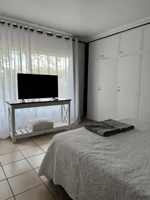 a bedroom with a bed and a flat screen tv at Atterbury Value Bed and Breakfast Garsfontein in Pretoria