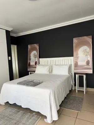 a bedroom with a large white bed with black walls at Atterbury Value Bed and Breakfast Garsfontein in Pretoria