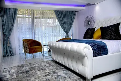 a bedroom with a large white bed and a chair at Beyond Borders Guest House in Polokwane