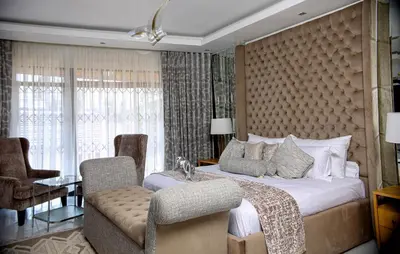 a bedroom with a king sized bed and a chair at Beyond Borders Guest House in Polokwane