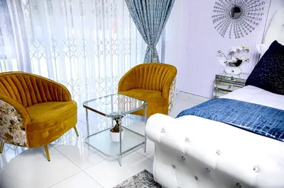 a bedroom with a bed and two chairs and a table at Beyond Borders Guest House in Polokwane
