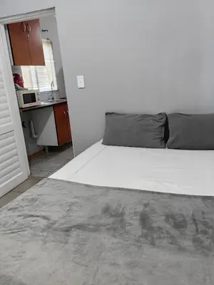 a white bed in a white room with a kitchen at Calm Corner in Pretoria