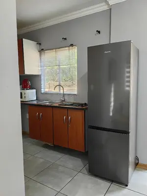 a kitchen with a stainless steel refrigerator and wooden cabinets at Calm Corner in Pretoria
