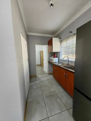 a kitchen with white cabinets and a tile floor at Calm Corner in Pretoria