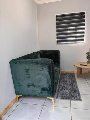 a green couch in a living room with a table at Calm Corner in Pretoria