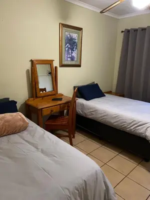 a room with two beds and a desk and a mirror at ForgetMeNot Guesthouse Lydenburg in Lydenburg