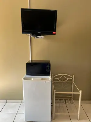 a tv on a wall with a refrigerator and a tv at ForgetMeNot Guesthouse Lydenburg in Lydenburg