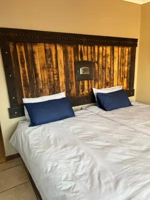 a large bed with two blue pillows on it at ForgetMeNot Guesthouse Lydenburg in Lydenburg