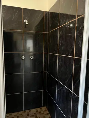 a black tiled shower with black tiles at ForgetMeNot Guesthouse Lydenburg in Lydenburg
