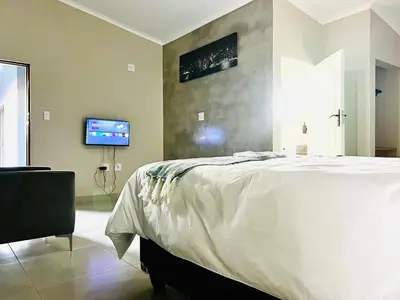a bedroom with a bed and a tv on a wall at TLS Cottages