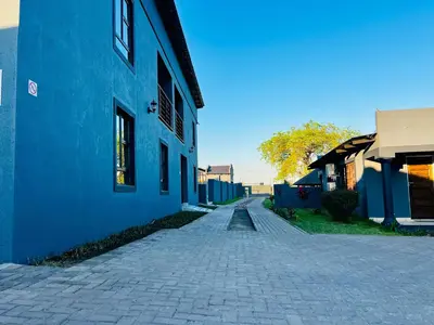 a cobblestone street next to a blue building at TLS Cottages