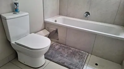 a bathroom with a white toilet and a bath tub at The Perfect Luxury Space at 93 on new in Midrand