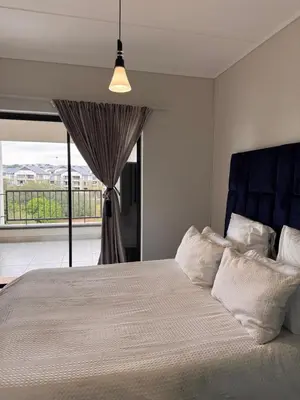 a bedroom with a bed with a blue headboard and a window at Staycation At Munyaka Estate in Midrand